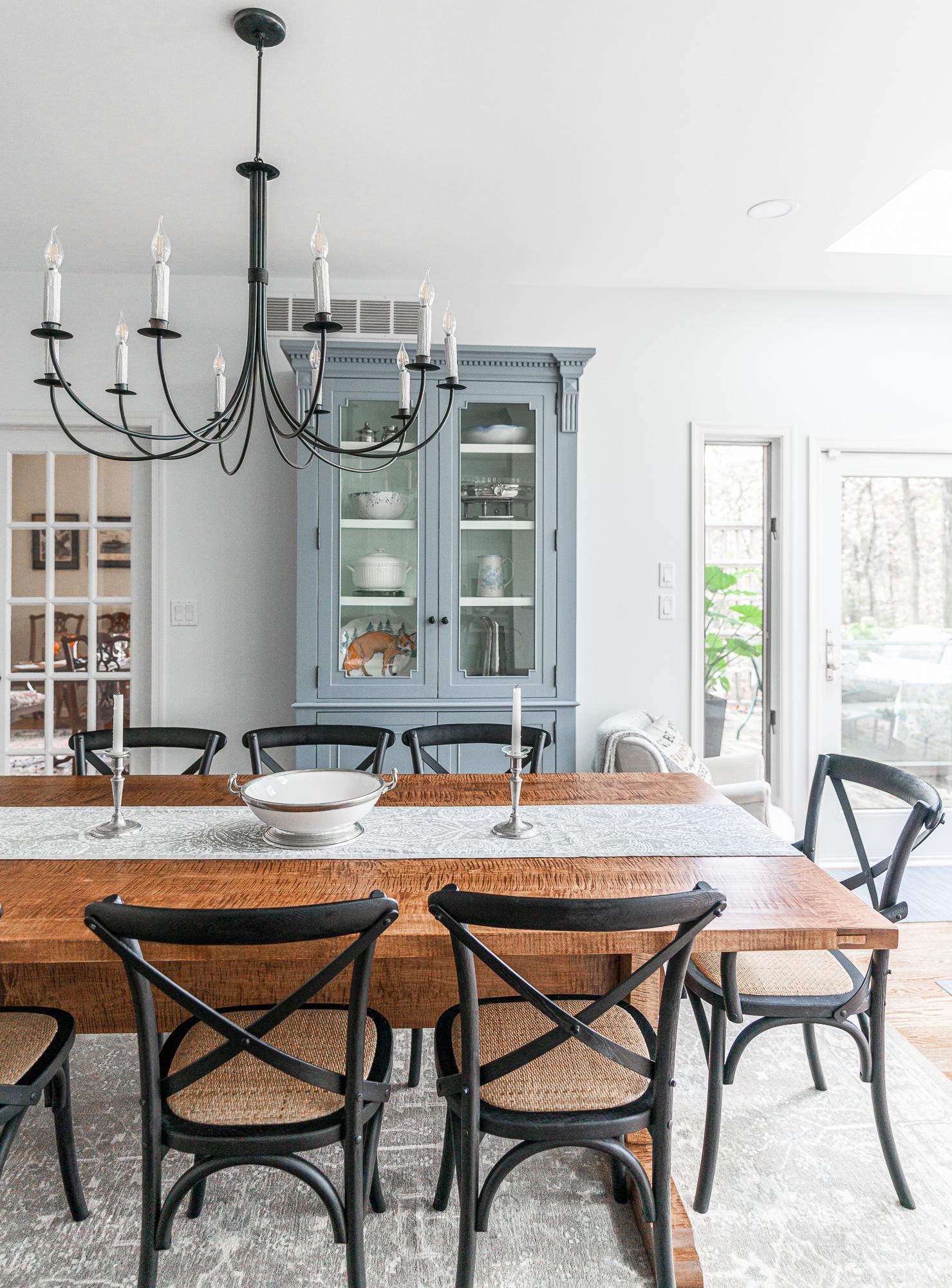 Wooden dining room table with chandelier and teal china cabinet
