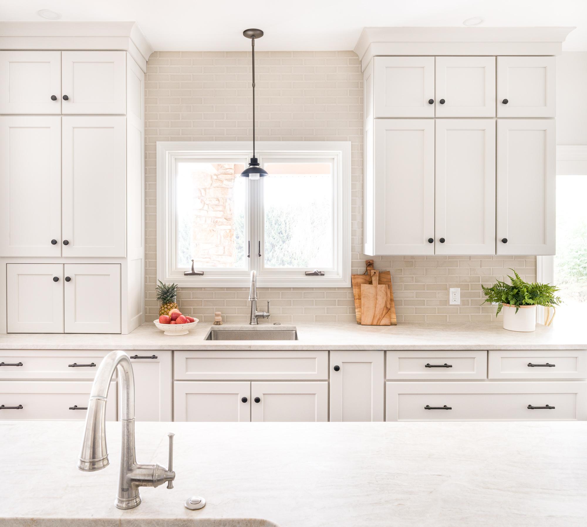 White cabinets and kitchen counters with cutting boards and plants